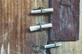 Three small rolls of white papers notification inserted into old rusty padlock hasp on the old wooden door. Bulletin sticking out