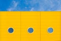 Three small round windows on a yellow wall opposite the blue sky Royalty Free Stock Photo