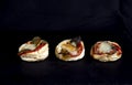 Three small rustic savory pastries, with puff pastry, tomatoes, mozzarella, and courgette flowers, against a black background