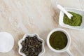 Three small white bowls with dry green tea leaves, green tea face or hair mask and matcha powder. Natural beauty treatment Royalty Free Stock Photo