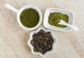 Three small white bowls with dry green tea leaves, green tea mask and matcha powder. Natural beauty treatment, skip-care Royalty Free Stock Photo