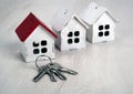 Three small wooden houses and house keys on a wooden background Royalty Free Stock Photo