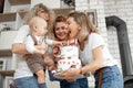 Three smiling beautiful middle-aged and young women congratulate cute little one-year-old boy touching macaroon cake. Royalty Free Stock Photo