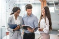 Three smiling business people discussing document in the modern office. Royalty Free Stock Photo