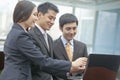 Three smiling business people looking at laptop and pointing, indoors Royalty Free Stock Photo