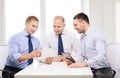 Three smiling businessmen with tablet pc in office