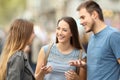 Three smiling friends talking standing on the street