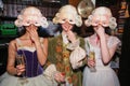 Three smiling girls in medieval costumes and masquerade masks are making fun at the backstage of the Bolshoy Theater