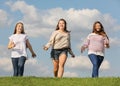 Three smiling girls run at grass Royalty Free Stock Photo