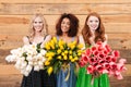 Three smiling women showing bouquets of flowers at camera Royalty Free Stock Photo