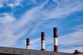 Three smoke pipe made of bricks standing tall with white clouds and blue sky