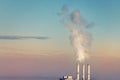 Three smoking stack pipes making clouds of white smoke with dramatic sunset sky background. Industrial minimalistic