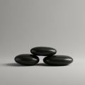 Three smooth, black pebbles are stacked in a triangular formation on a light gray Royalty Free Stock Photo