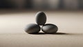Three smooth dark gray stones are arranged on a sandy surface Royalty Free Stock Photo