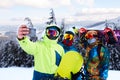 Three snowboarders taking selfie with smartphone camera at ski resort. Friends photographing for social network sharing Royalty Free Stock Photo