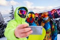 Three snowboarders taking selfie with smartphone camera at ski resort. Friends photographing for social network sharing