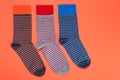 Three socks with colored stripes lined up in a row on orange background, concept Royalty Free Stock Photo