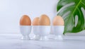 Three soft-boiled eggs in white egg cups on marble surface Royalty Free Stock Photo