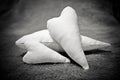 Three soft handmade hearts sewn from flax, lie on the rug. Vignetted black and white photo with cinematic grain