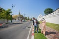 Three South Asian tourists with cameras happily hitchhiking the road behind Wat Pho during their long weekend happily. in Bangkok