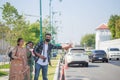 Three South Asian tourists with cameras happily hitchhiking the road behind Wat Pho during their long weekend happily. in Bangkok