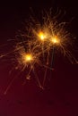 Three sparklers burning against a dark red background, party con Royalty Free Stock Photo