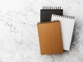three spiral notebook, black, white and brown, in hard covers on a gray marble background