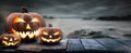 Three spooky halloween pumpkins, Jack O Lantern, with an evil face and eyes on a wooden bench.