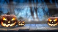 Three spooky halloween pumpkins, Jack O Lantern, with evil face and eyes on a wooden bench