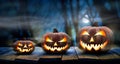 Three spooky halloween pumpkins in a row, Jack O Lantern, with evil face and eyes