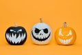Three Spooky Halloween pumpkins with scary face expressions over orange background. Halloween concept.