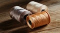 Three spools of thread in beige, tan, and light brown tones placed on a wooden surface Royalty Free Stock Photo