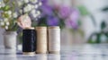Three spools of thread in black, beige, and white placed on a marble surface. Soft-focus flowers in the background Royalty Free Stock Photo