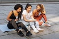 Three sporty women having fun and laughing looking smartphone after urban fitness workout. Royalty Free Stock Photo