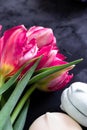 Three spring pink tulips laying on the dark grey backdrop and blurred hyacinth in the background