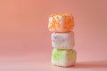 Three square marshmallows stacked on top of each other on a pink background. The marshmallow on top has orange sprinkles, the Royalty Free Stock Photo