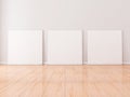 Three Square white Canvases Mockup stand on wooden floor in empty room