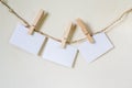 Three squares of blank paper, pegged to a string washing line