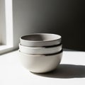 Three stacked ceramic bowls in shades of gray and white are placed on a white Royalty Free Stock Photo
