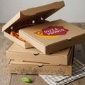 Boxes on a wooden table, with the top box slightly open, revealing a pizza Royalty Free Stock Photo