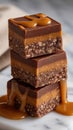 Three stacked squares of caramel chocolate dessert featuring rich layers and a decadent caramel drizzle on a marble Royalty Free Stock Photo