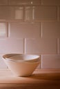 Three stacked white porcelain bowls with warm light on wood planks