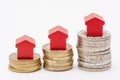 Three stacks of euro coins with red arrow-shaped houses on top