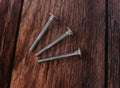 Three stainless steel bolts lying flat on wood textured table