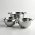 Three stainless steel colanders in various sizes sit on a clean white surface. These kitchen tools are perfect for draining pasta Royalty Free Stock Photo
