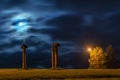 Three statues in field at night