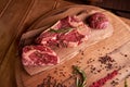 Three steaks of rib eye on a wooden cutting board with a sprig of rosemary, colored peppercorns, dried pickles and a glass of wine Royalty Free Stock Photo