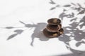 Three stones are stacked one on top of the other in the shadows of leaves and sunlight on a white marble background Royalty Free Stock Photo