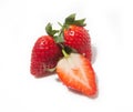 Three strawberries, one half and two whole ones behind it, are isolated on a white background Royalty Free Stock Photo