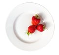 Three strawberries on a white plate isolated on white background Royalty Free Stock Photo